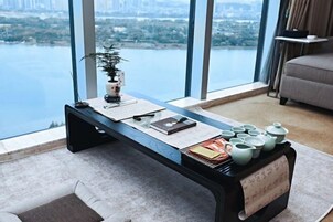 Escritorio moderno con vistas a un paisaje urbano y al agua, una planta y un juego de té.