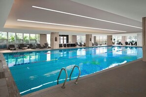 Ein Innenpool mit klarem Wasser, einer Poolleiter und sonnendurchfluteten Sitzbereichen.