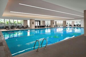 Ein Innenpool mit klarem Wasser, einer Poolleiter und sonnendurchfluteten Sitzbereichen.