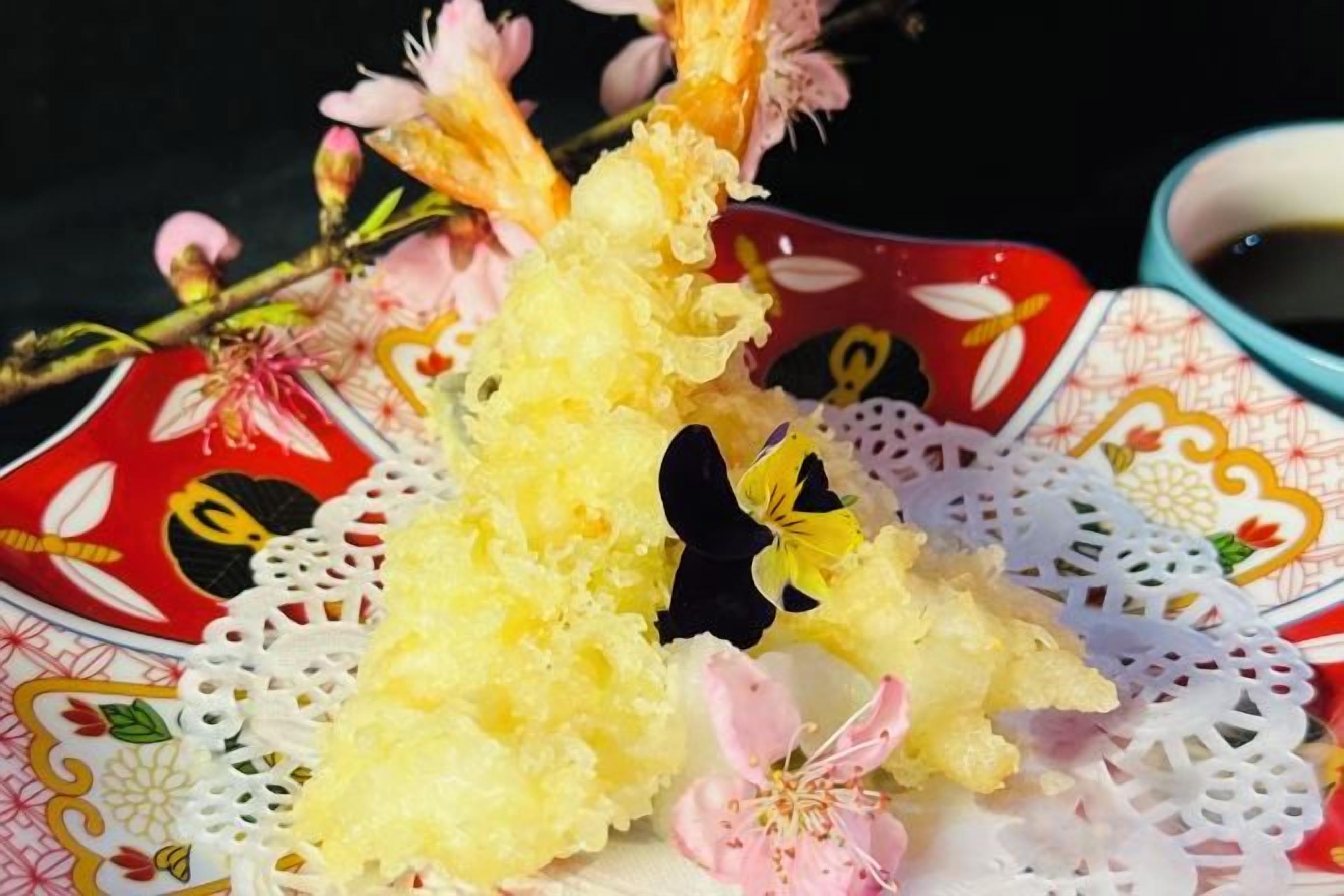 A decorative plate with a floral pattern and a piece of yellow food on a lace doily.