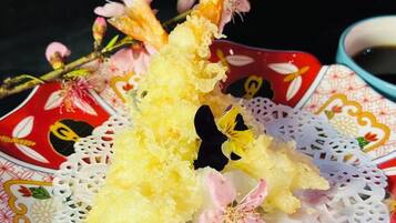 A decorative plate with a floral pattern and a piece of yellow food on a lace doily.