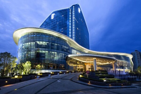 A modern hotel with a curved glass facade and a prominent tower. - Suining Dongxu Soluxe International Grand Hotel (SUINING)