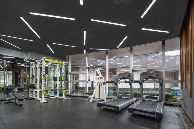 Un gimnasio moderno con cintas de correr, máquinas de pesas y un espejo grande.