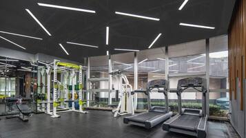 Un gimnasio moderno con cintas de correr, máquinas de pesas y un espejo grande.