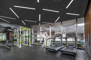 Un gimnasio moderno con cintas de correr, máquinas de pesas y un espejo grande.