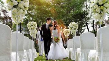 A wedding ceremony with white floral arrangements and chairs.