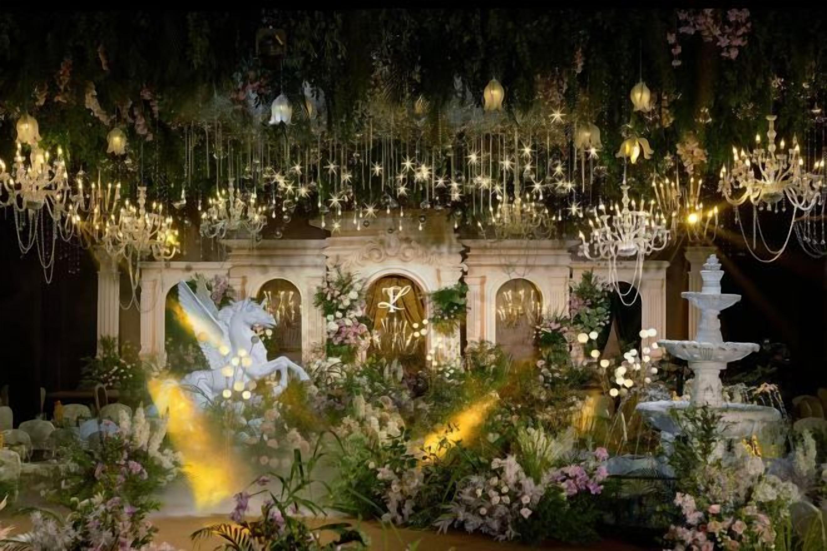 Un salón imponente con una fuente, candelabros ornamentados y una estatua de una criatura alada.