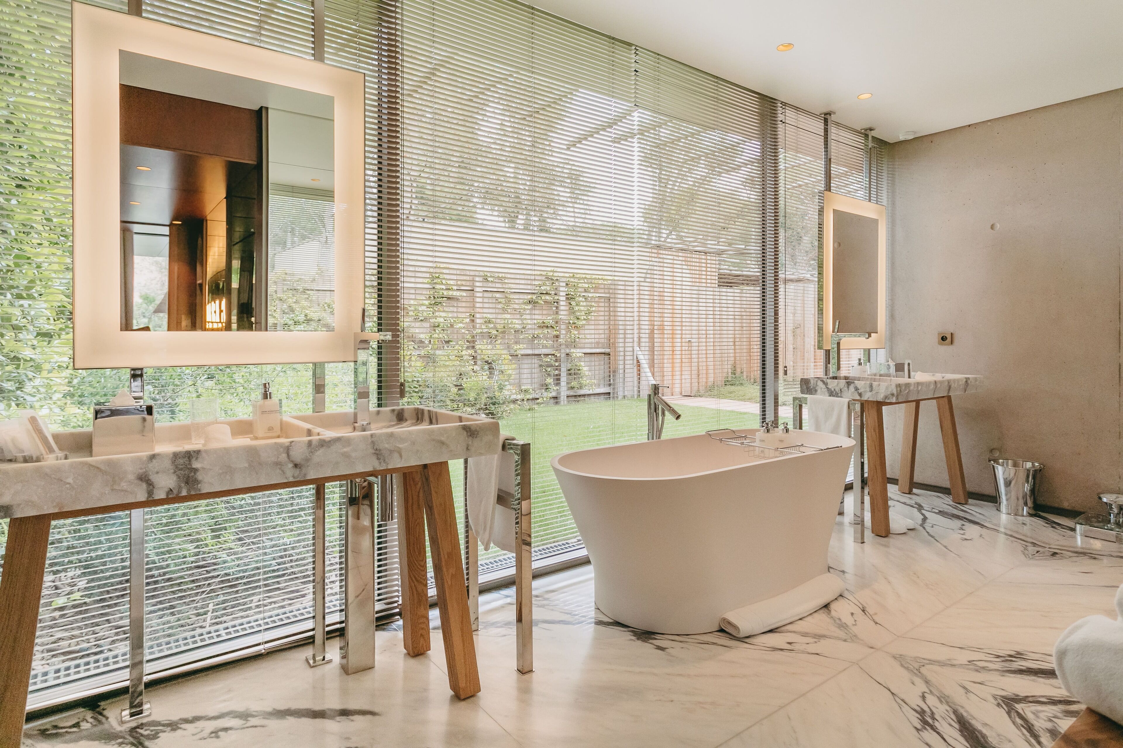 A modern bathroom with a freestanding bathtub, a large mirror, and a marble countertop.
