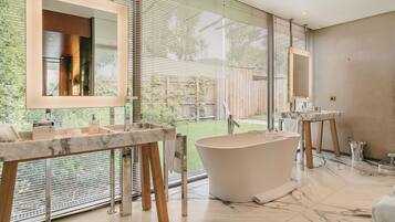 A modern bathroom with a freestanding bathtub, a large mirror, and a marble countertop.