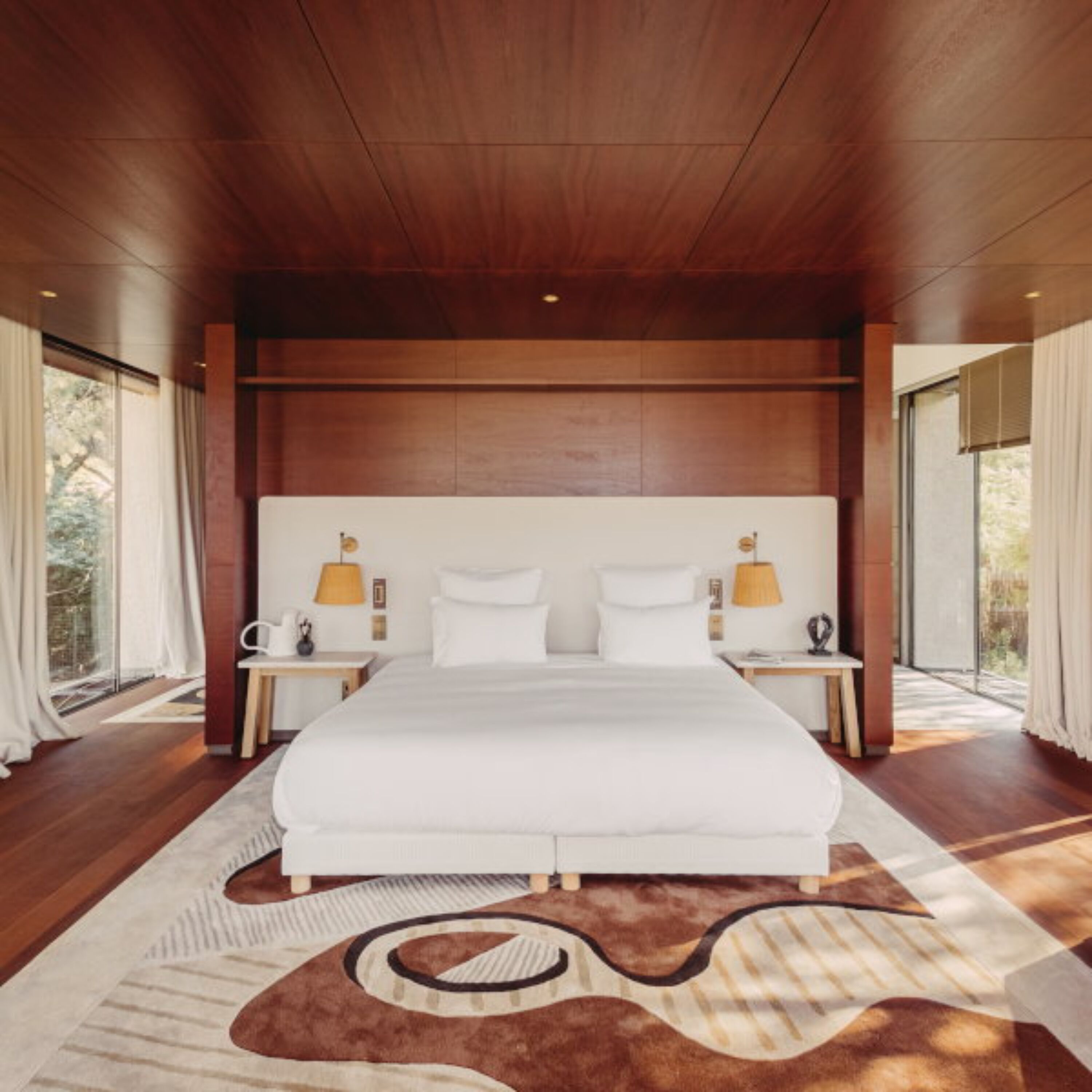 A modern bedroom with a large bed, wooden ceiling, and two bedside lamps.