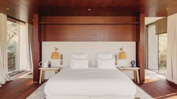 A modern bedroom with a large bed, wooden ceiling, and two bedside lamps.