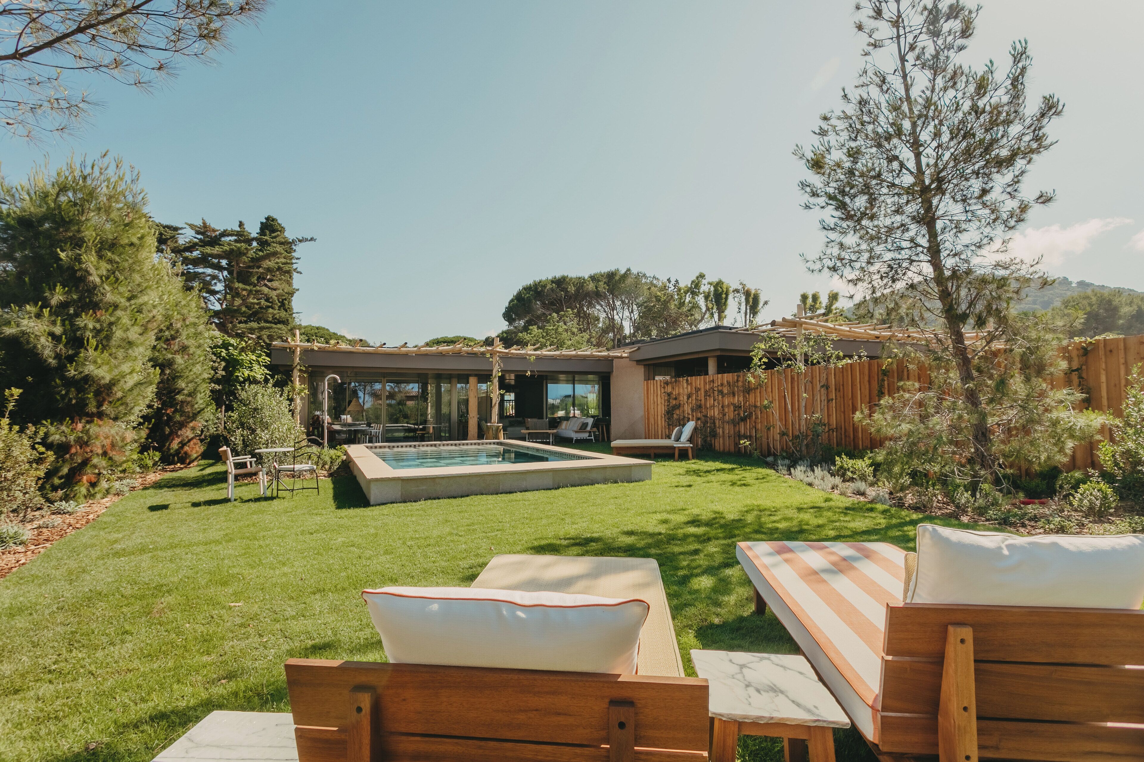 Un jardin avec une piscine, une terrasse en bois et des chaises longues.