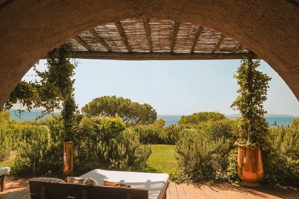 Un espace extérieur aménagé avec des sièges, offrant une vue sur la mer, agrémenté d’une pergola et d’une terrasse en bois.