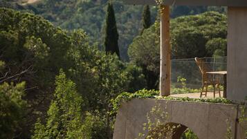 A concrete structure with a chair and a table, overlooking a lush green landscape.