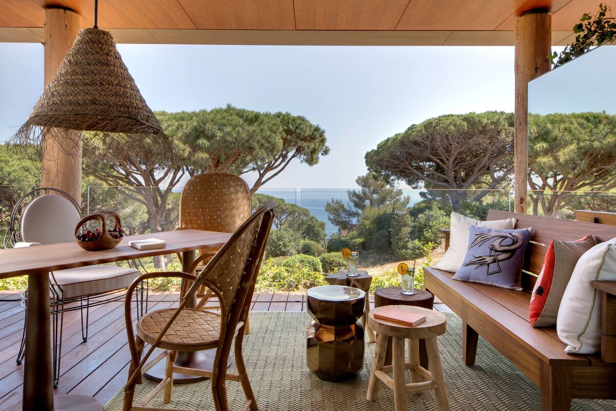 Une terrasse en bois avec une table, des chaises et un banc.