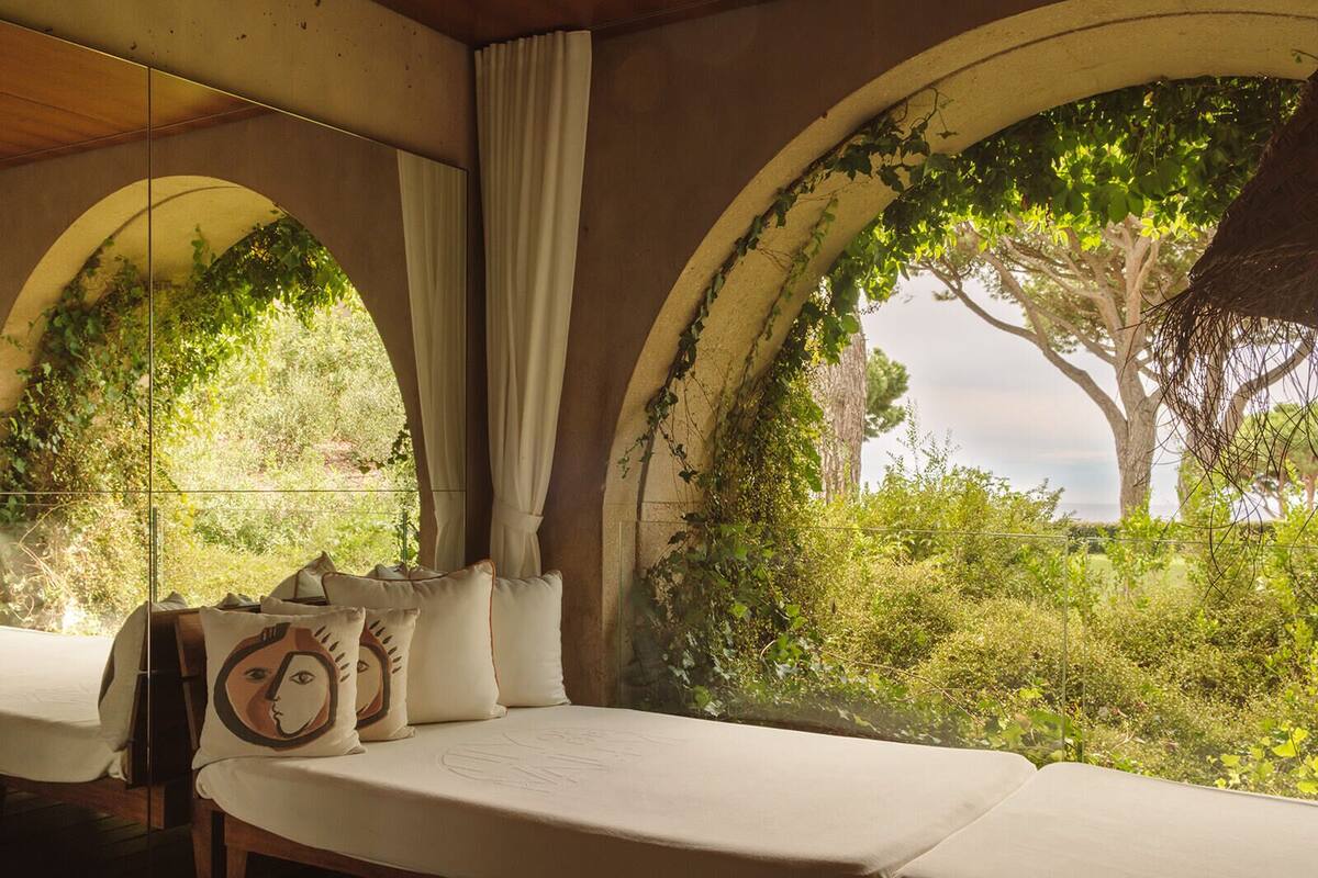 Une chambre avec un lit, une fenêtre avec des rideaux et une vue sur la verdure et les arbres.