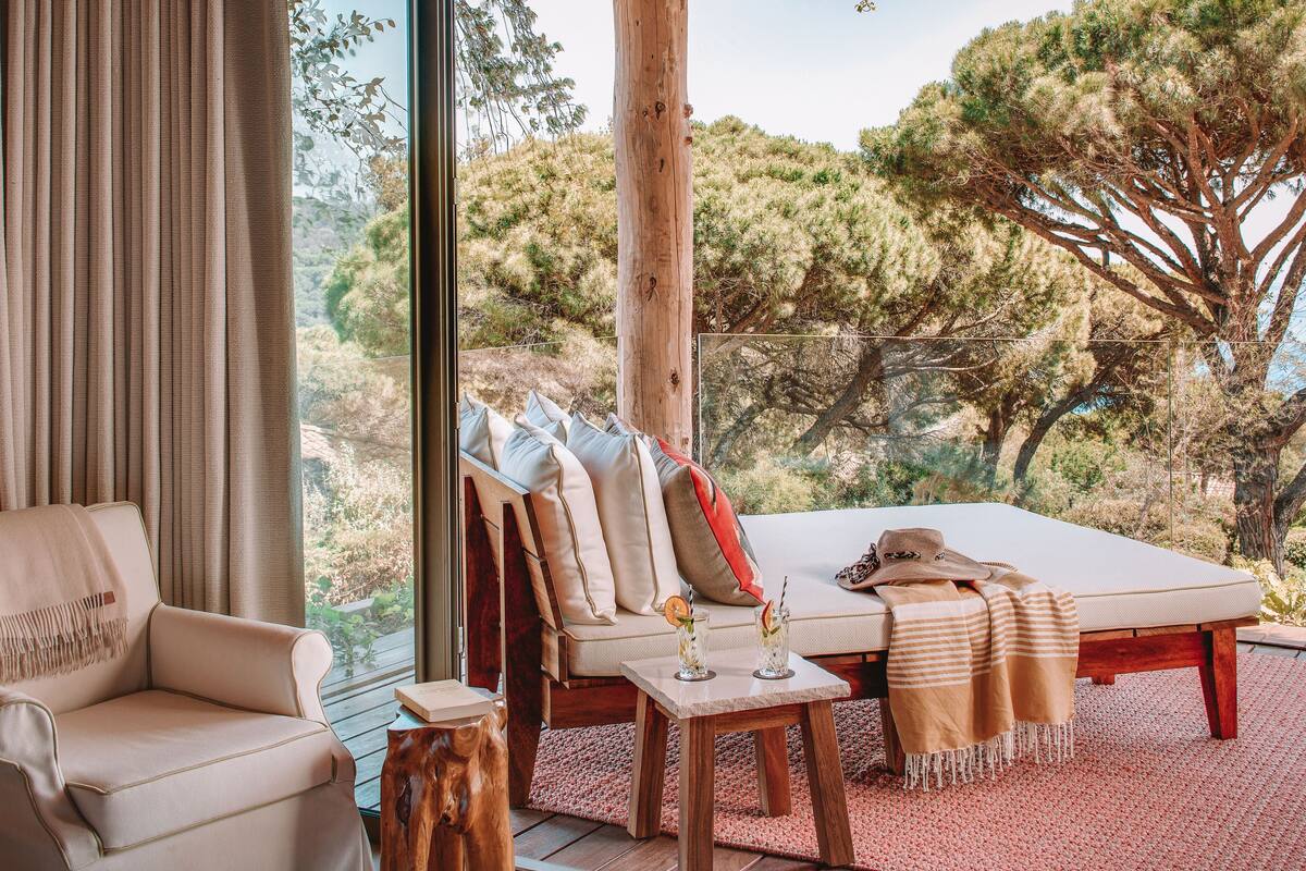 Une pièce chaleureuse avec un canapé, une table avec des boissons et une vue sur les arbres.