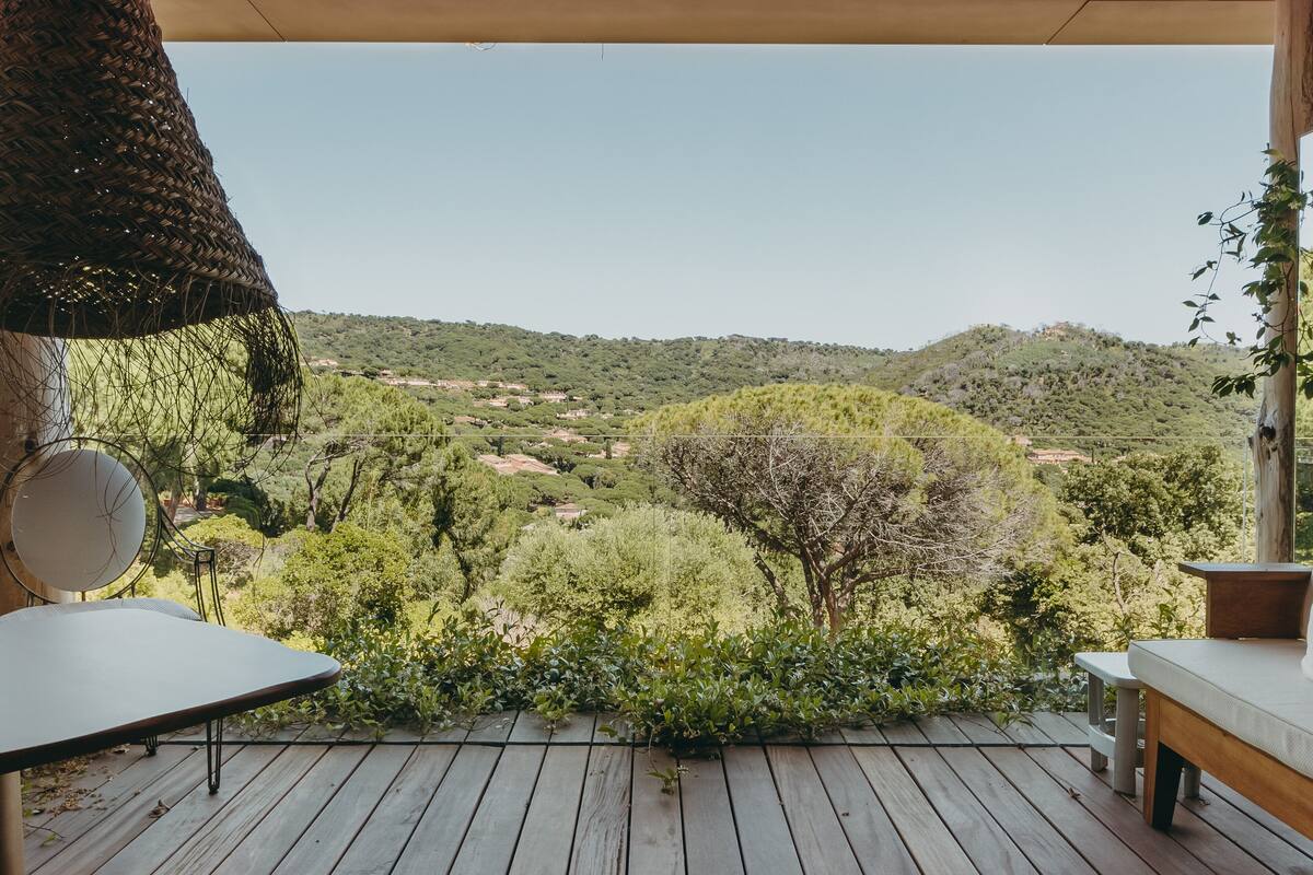 Une terrasse en bois offrant une vue sur un paysage vallonné.