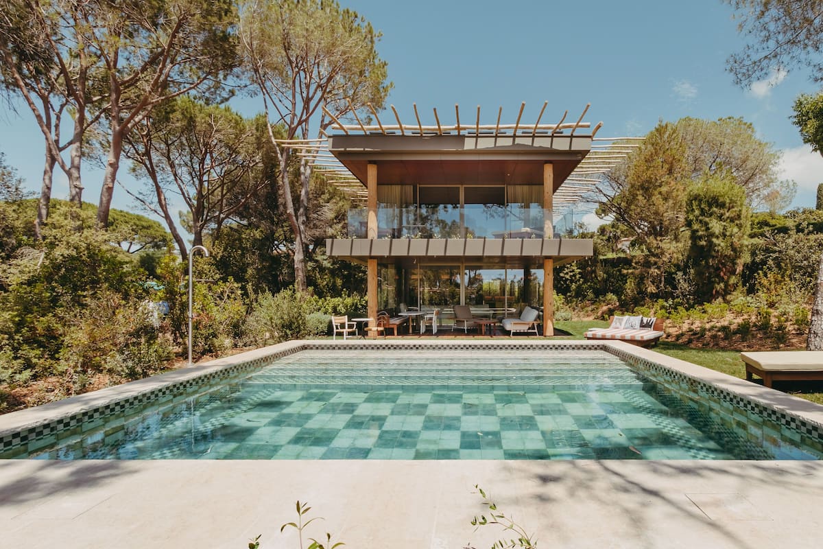 Une maison moderne avec une piscine, entourée d’arbres et de verdure.