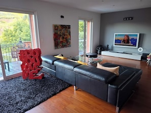 Un salon moderne avec un canapé d’angle, une table basse en verre et un téléviseur à écran plat.