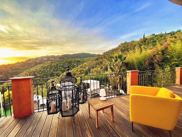 Une terrasse en bois avec des meubles d’extérieur, une chaise jaune et des cages à oiseaux.