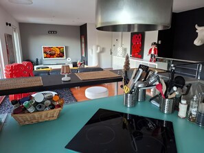 Une cuisine moderne dotée d’un plan de travail noir, d’appareils électroménagers en acier inoxydable et d’une variété d’ustensiles de cuisine.