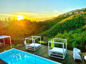 A pool area with two white sun loungers and a pool. - Villa Colina (Mandelieu-La-Napoule)
