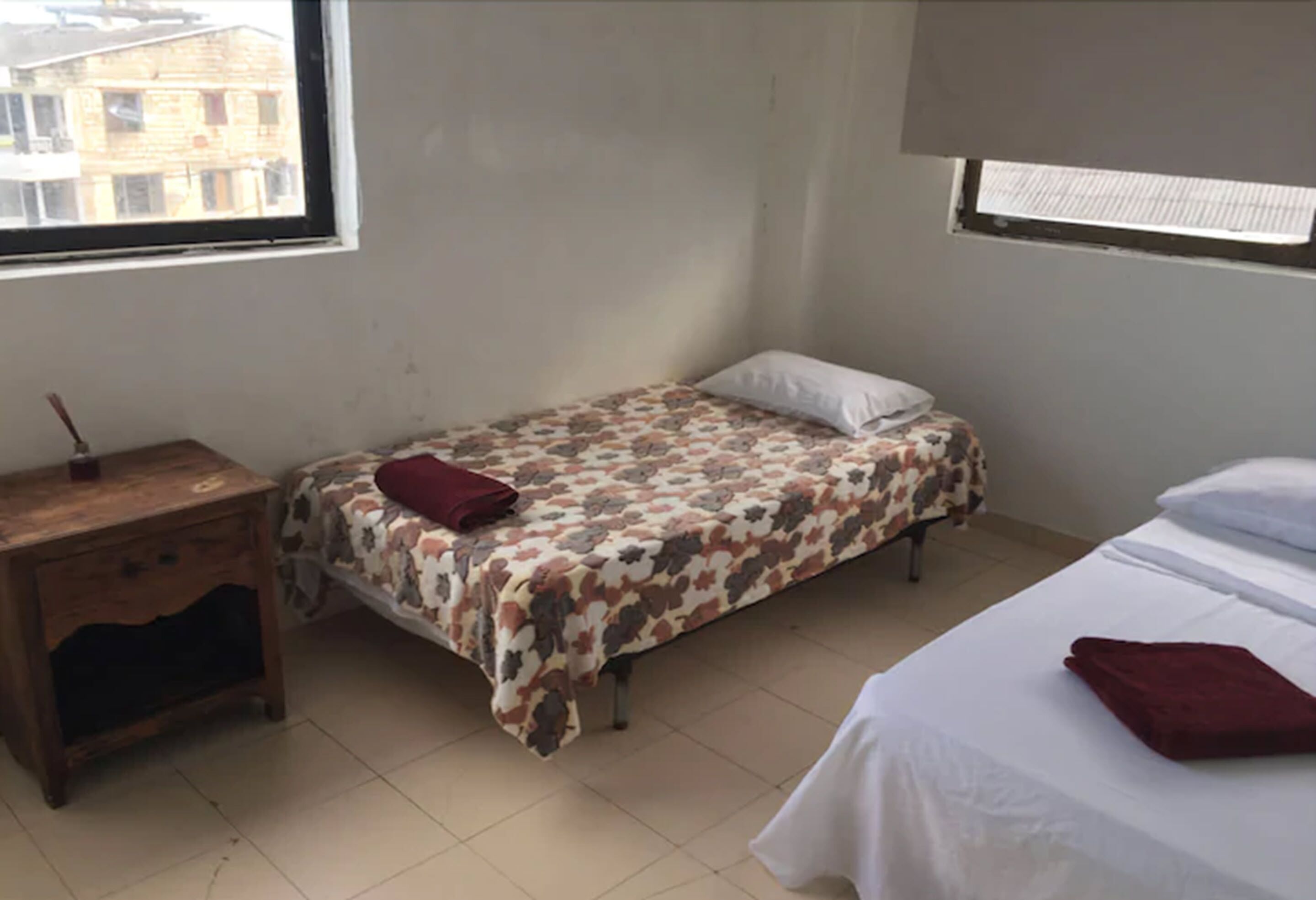 Una habitació petita i senzilla amb un llit, una tauleta de nit i una finestra.