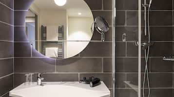 Une salle de bain avec un lavabo blanc, un miroir à main, une douchette et un porte-serviettes.