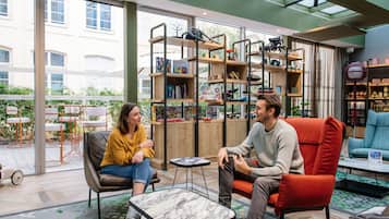 A modern indoor space with a glass ceiling, a wooden bookshelf, and a seating area with a table.