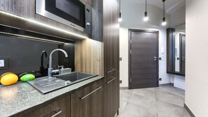 Eine moderne Küche mit integriertem Mikrowellenherd, Spüle aus Edelstahl und Holzschränken.
