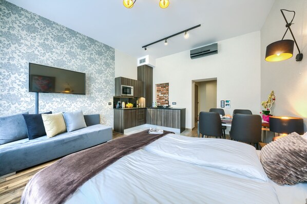 A modern hotel room with a large bed, a sofa, a dining area, and a kitchenette. - Abba Apartments (Wroclaw)