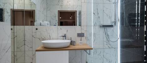 A modern bathroom with a marble vanity, a glass shower enclosure, and a large mirror.