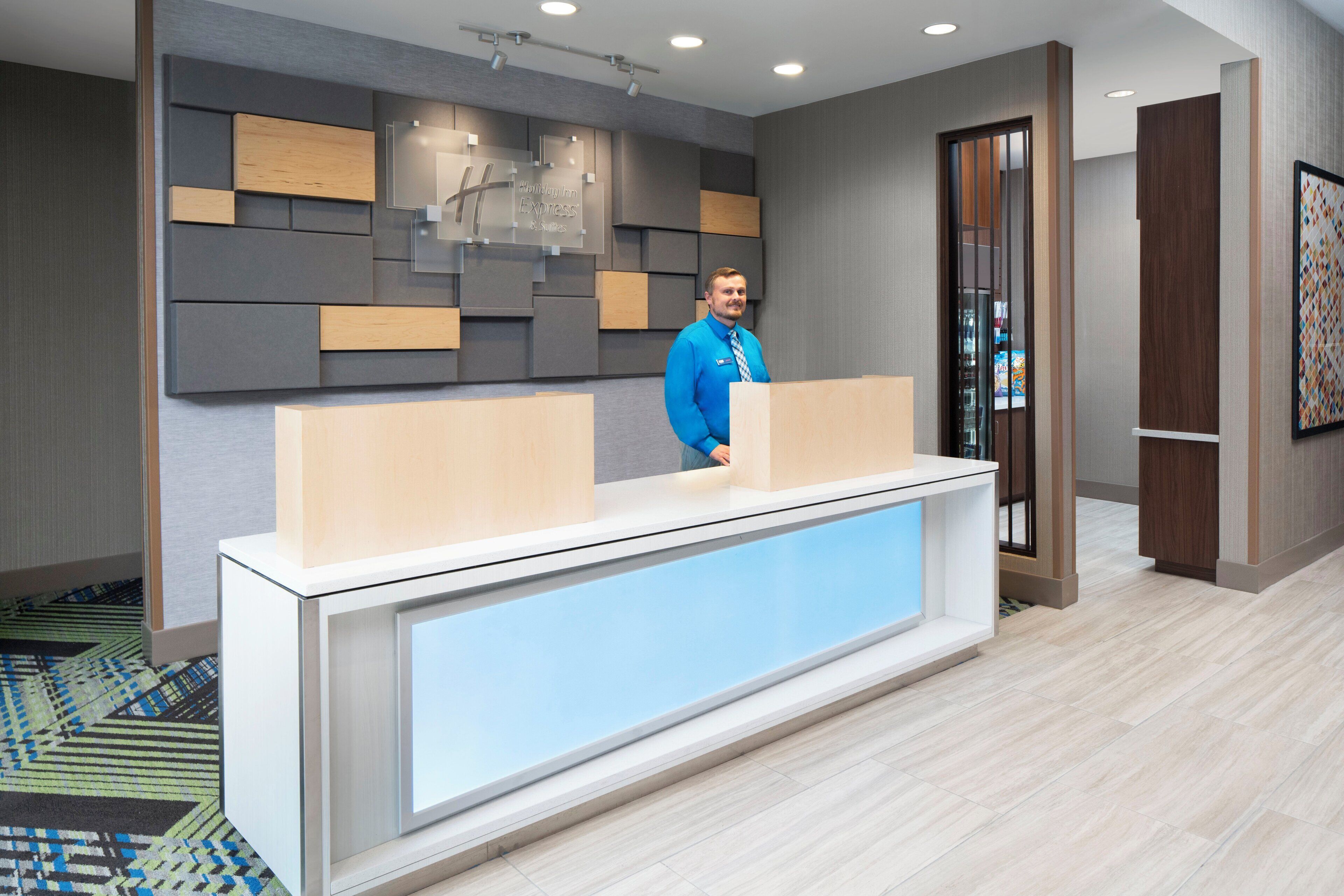 A reception desk with a modern design, a man standing behind it, and a patterned carpet.