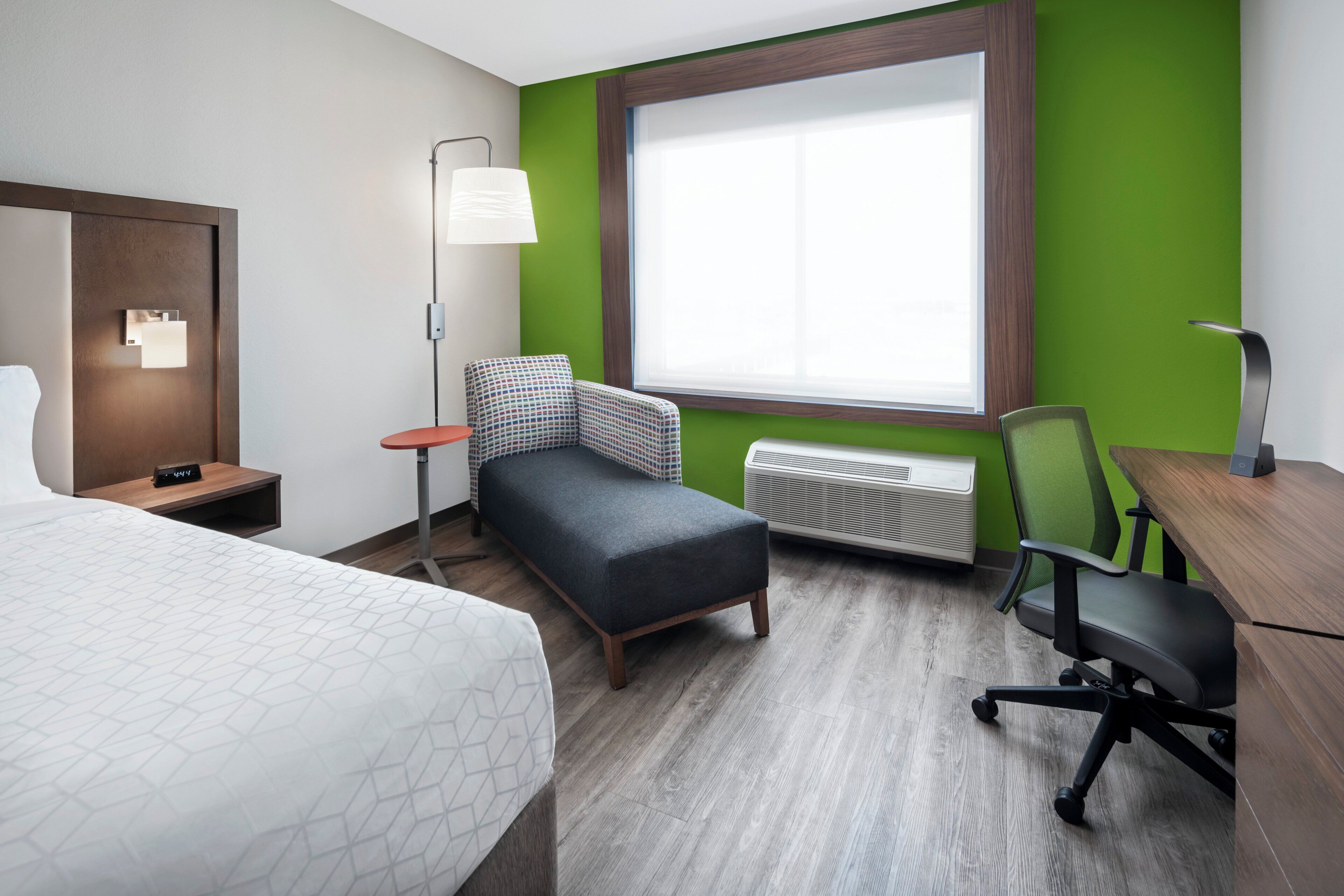 Une chambre d’hôtel équipée d’un lit, d’un bureau, d’une chaise, d’une lampe, d’une fenêtre et d’un radiateur.
