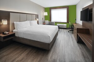 Una habitación de hotel con una cama grande, un escritorio, una silla, un televisor y una ventana.