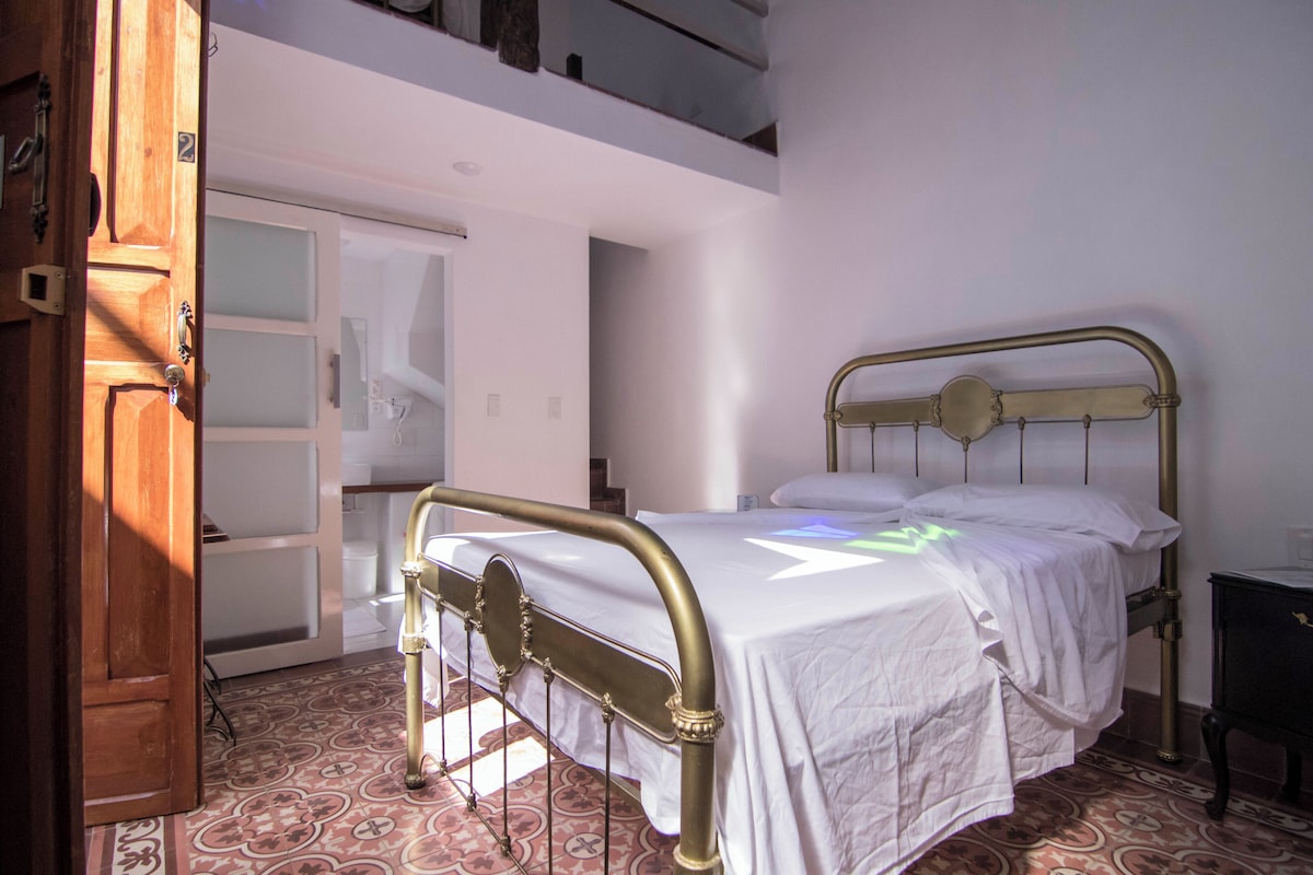 Ein Schlafzimmer mit einem Bett, einer Holztür und einem Fliesenboden.