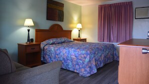 Ein Hotelzimmer mit einem Bett, zwei Nachttischen mit Lampen, einer Holzkommode und einem Sessel.