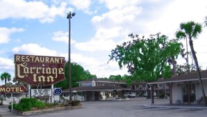 Ein Restaurant namens 'Cottage Inn' mit einem Motelzeichen, einem freundlichen Willkommensschild und blauem Himmel.