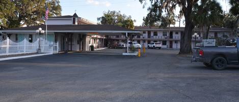 A motel with a white picket fence, a gas station, and a parking lot.