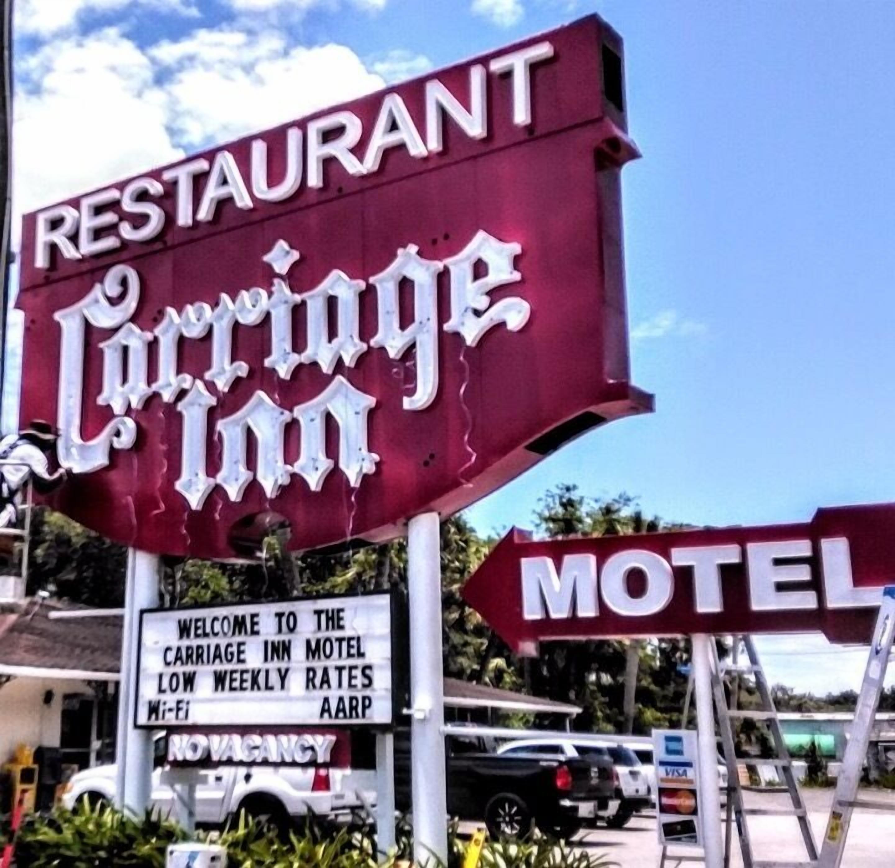 Señal para el motel Carrige Inn, con un letrero que dice 'RESTAURANTE' arriba y uno que dice 'MOTEL' abajo.
