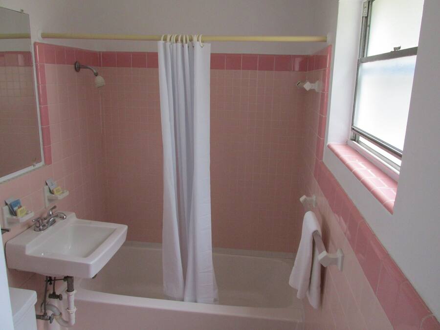 A bathroom with a shower, sink, and window.
