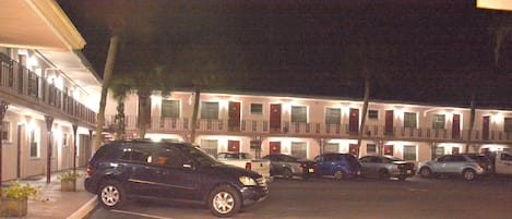 A row of motel buildings with multiple balconies and parked cars in front.