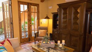 Una sala de estar acogedora con un sofá, una mesa de centro con adornos, una silla y un mueble de madera grande.