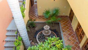 Un patio con una fuente, plantas en macetas y una escalera.