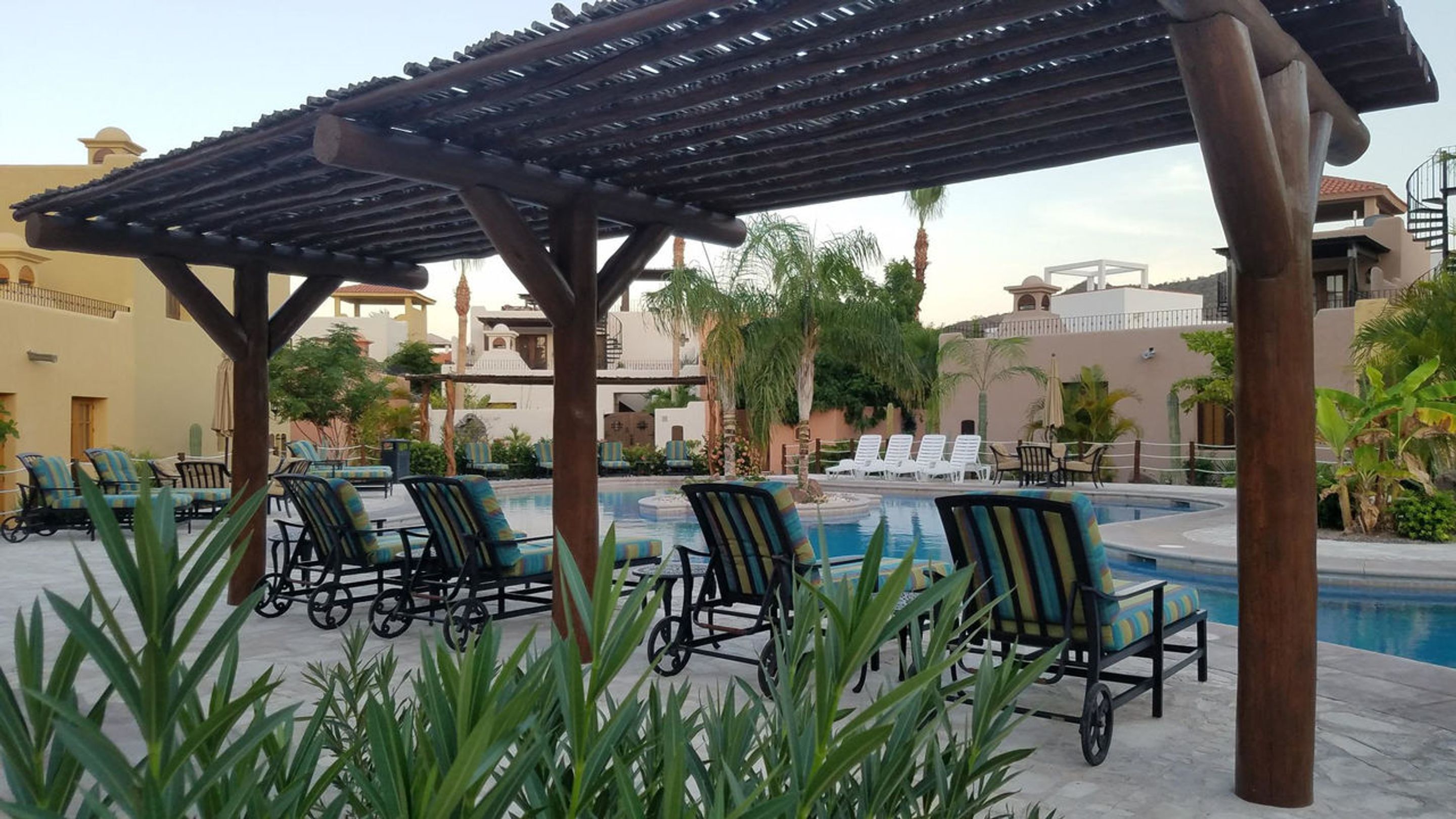 Een zwembadgedeelte met ligbedden en een pergola.