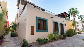 A two-story building with a beige facade, teal window frames, and a balcony with a railing. - Casa Corazon FN 164 2 BR by Casago (Loreto)