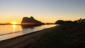 A coastal landscape with a sunset, a prominent rock formation, and a beach. - Casa Corazon FN 164 2 BR by Casago (Loreto)