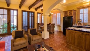 A spacious living area with a dining table, comfortable seating, and a kitchen area with wooden cabinets and a refrigerator. - Casa Corazon FN 164 2 BR by Casago (Loreto)
