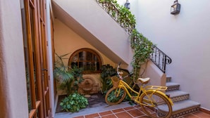 A yellow bicycle parked on a tiled staircase with a wrought iron railing, surrounded by greenery and a stone wall. - Casa Corazon FN 164 2 BR by Casago (Loreto)
